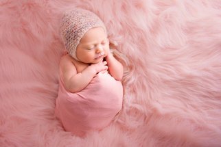 nyfødt jente med rosa blomsterkrans